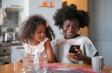 Mother and daughter at the table watching cell phone